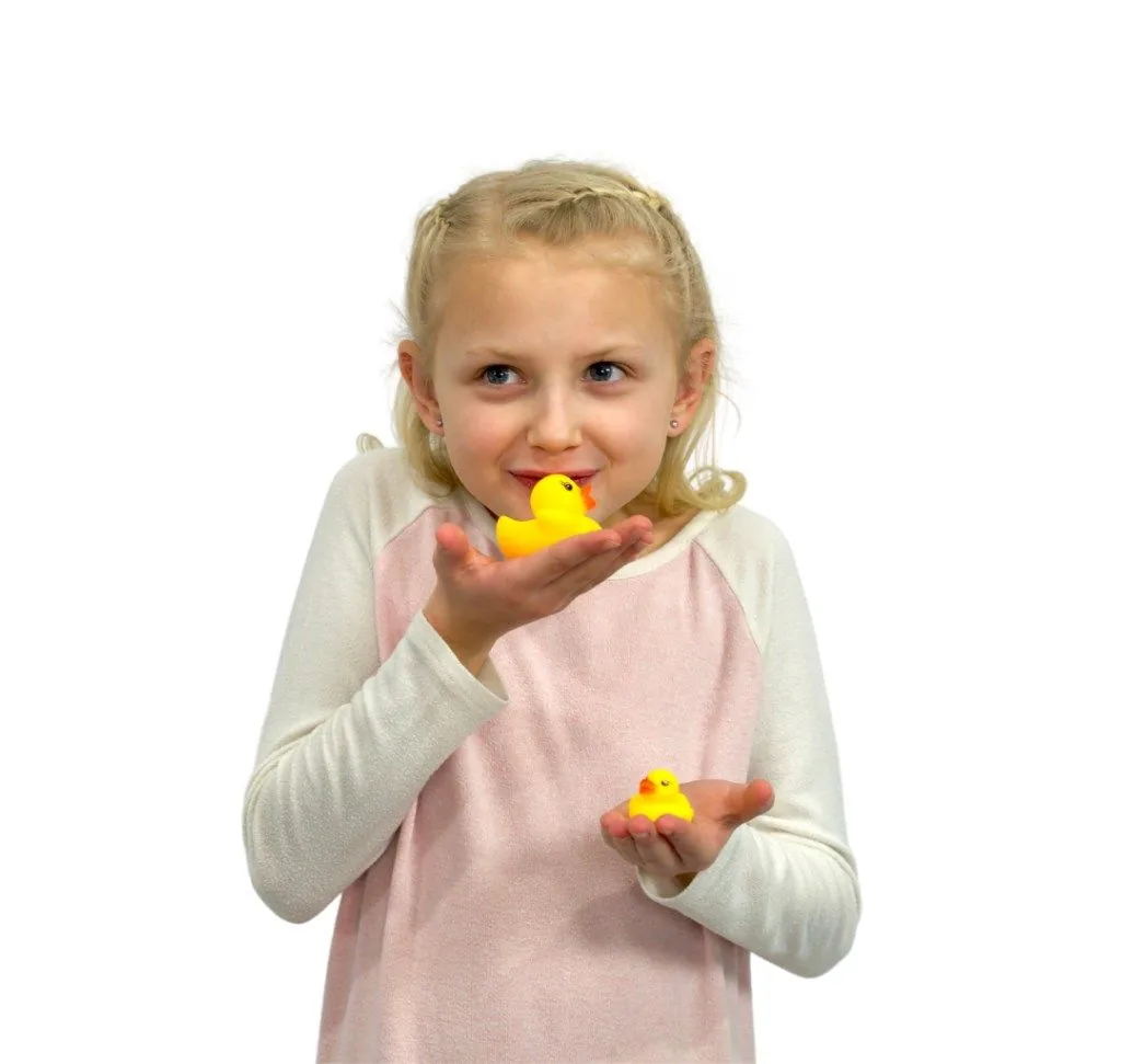 Child holding rubber ducks up to her face