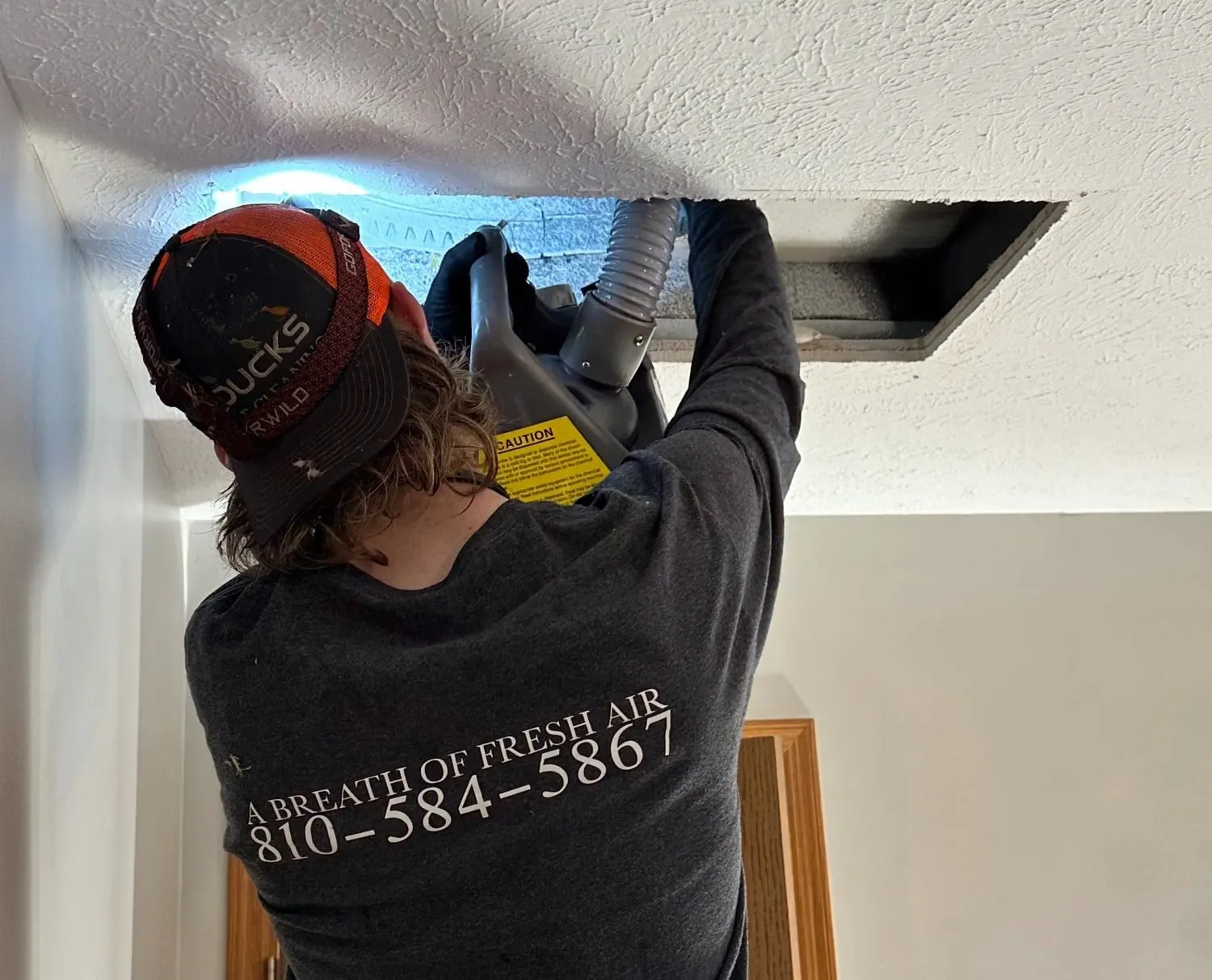 Air duct cleaning technician working a ceiling duct in Burton